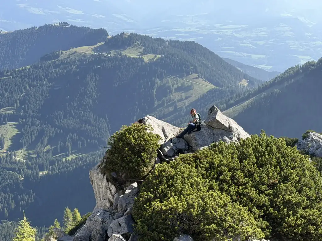 Een wandelaar op een rots met uitzicht over de Beierse Alpen en de vallei.