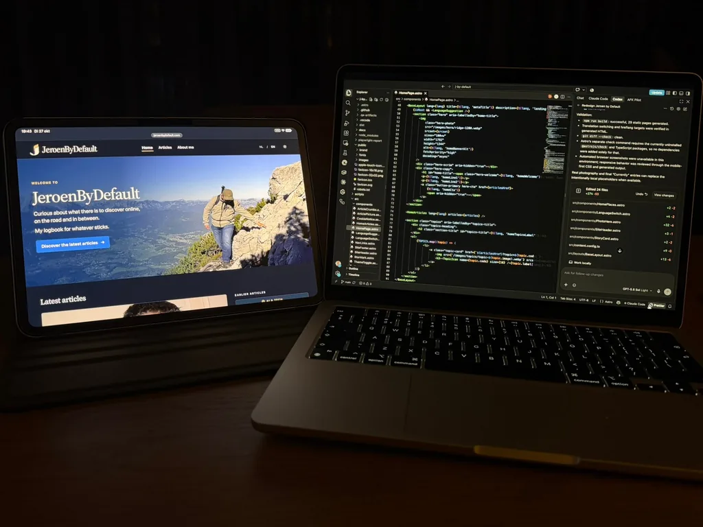 Een tablet en een laptop 's avonds naast elkaar op tafel. Op de tablet staat de Engelse homepage van JeroenByDefault, op de laptop de code van die pagina in VS Code met rechts een AI-assistent