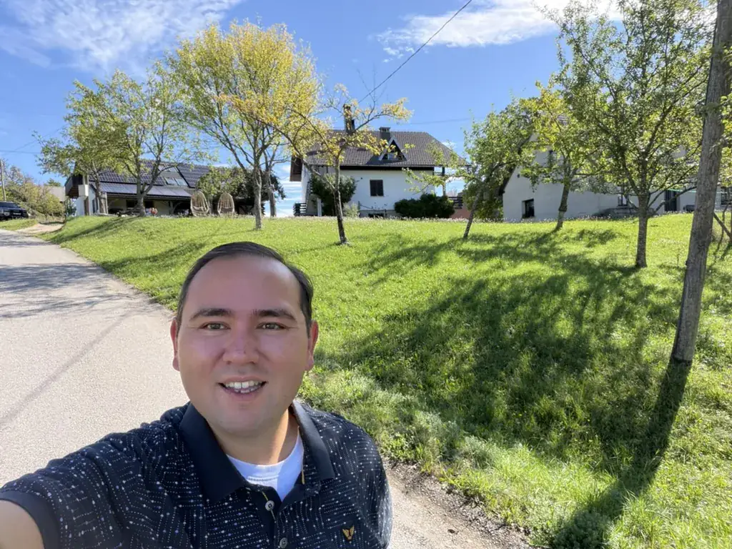 Jeroen op het terrein van Tourist Farm Strle in Osredek, met het huis en de boomgaard op de achtergrond.